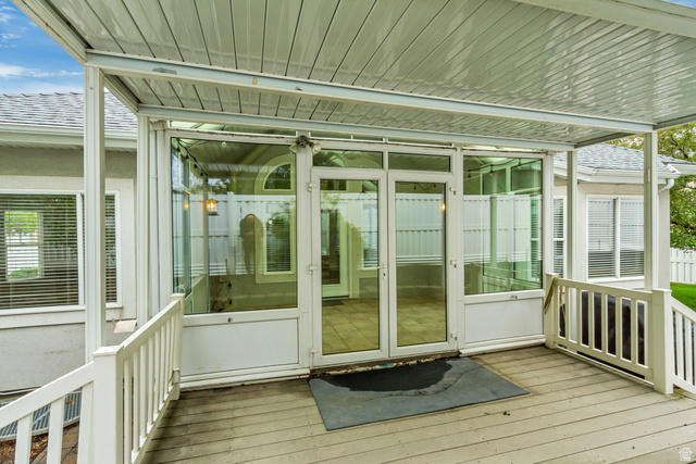 1433 Forge Way Draper, UT 84020 - Photo 29 of 29 Covered outdoor deck with white railing and direct access to a glass-enclosed room featuring a vaulted ceiling and an arched transom window