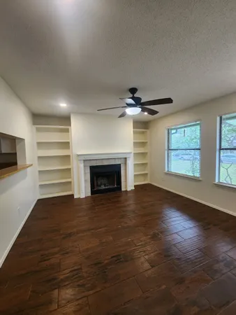 a view of empty room with wooden floor fireplace and window