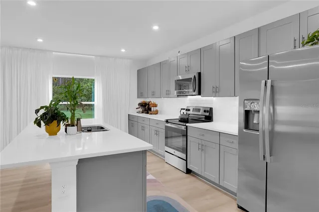 a kitchen with kitchen island a counter top space cabinets and stainless steel appliances