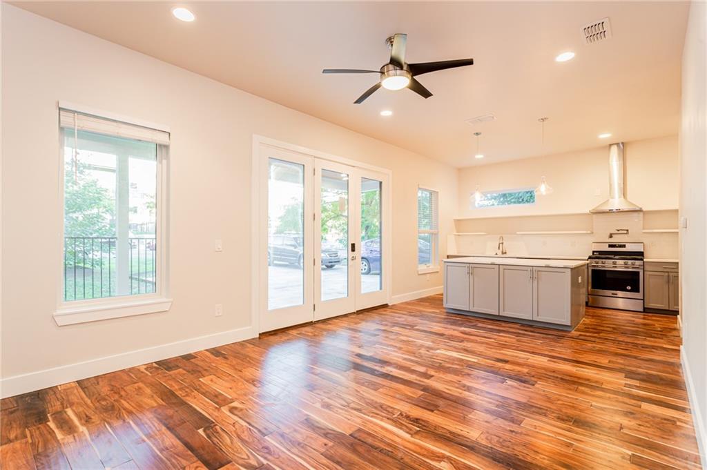 2509 Del Curto Road, Unit B Austin, TX 78704 - Photo 6 of 31 Kitchen with hanging light fixtures, wood finished floors, a ceiling fan, wall chimney exhaust hood, and stainless steel range with gas stovetop