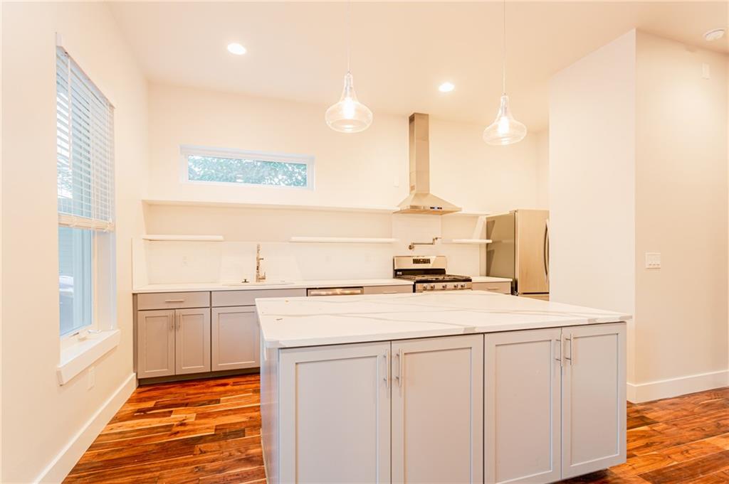 2509 Del Curto Road, Unit B Austin, TX 78704 - Photo 8 of 31 Kitchen with a sink, freestanding refrigerator, dark wood finished floors, wall chimney range hood, and stainless steel range oven