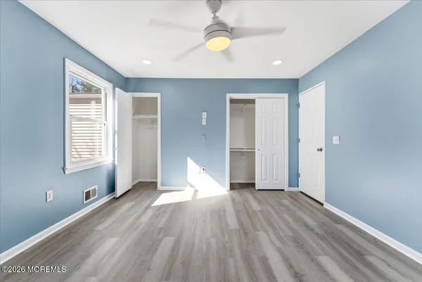 a view of empty room with wooden floor and fan