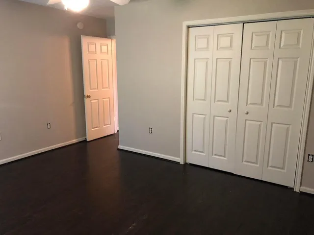 an empty room with wooden floor closet and windows