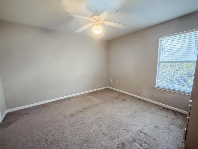 an empty room with a window and a fan