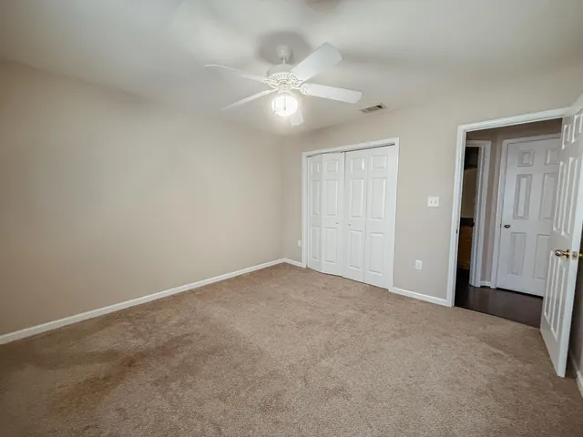 an empty room with closet and a ceiling fan