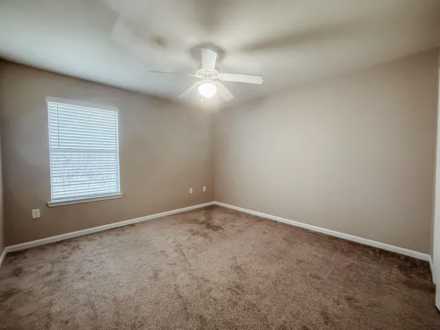 an empty room with a window and ceiling fan