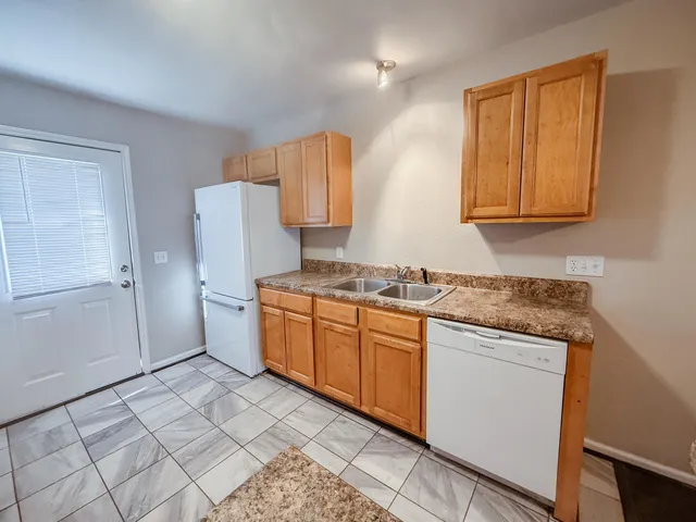 a kitchen with granite countertop a sink cabinets and stainless steel appliances