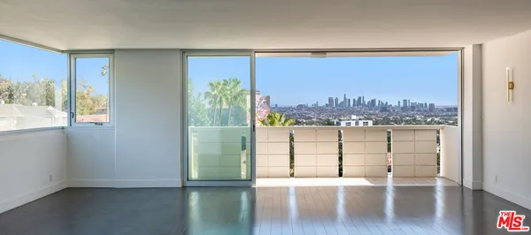 a view of a living room with a floor to ceiling window and wooden floor