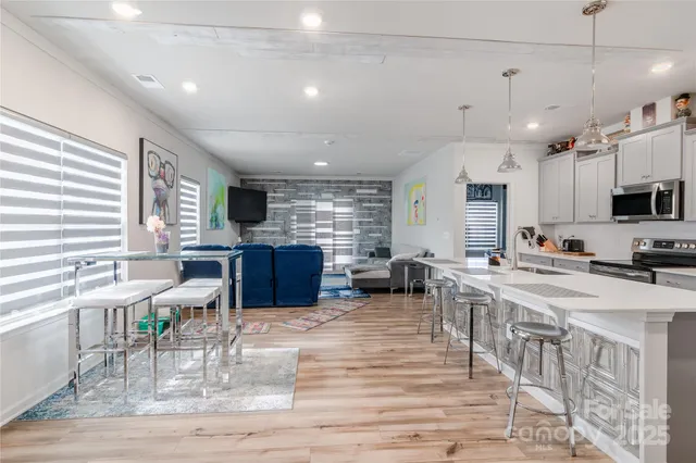 a kitchen with stainless steel appliances a white stove top oven a sink dishwasher and white cabinets with wooden floor