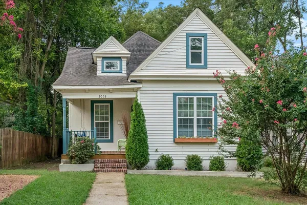 a front view of a house with a yard and potted plants