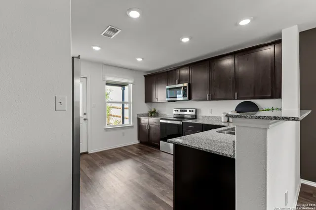 a kitchen with a refrigerator a stove top oven a sink and dishwasher with wooden floor