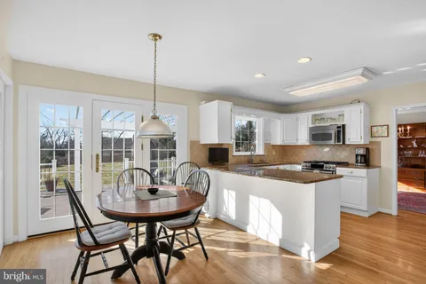 a kitchen with stainless steel appliances a dining table chairs and stove