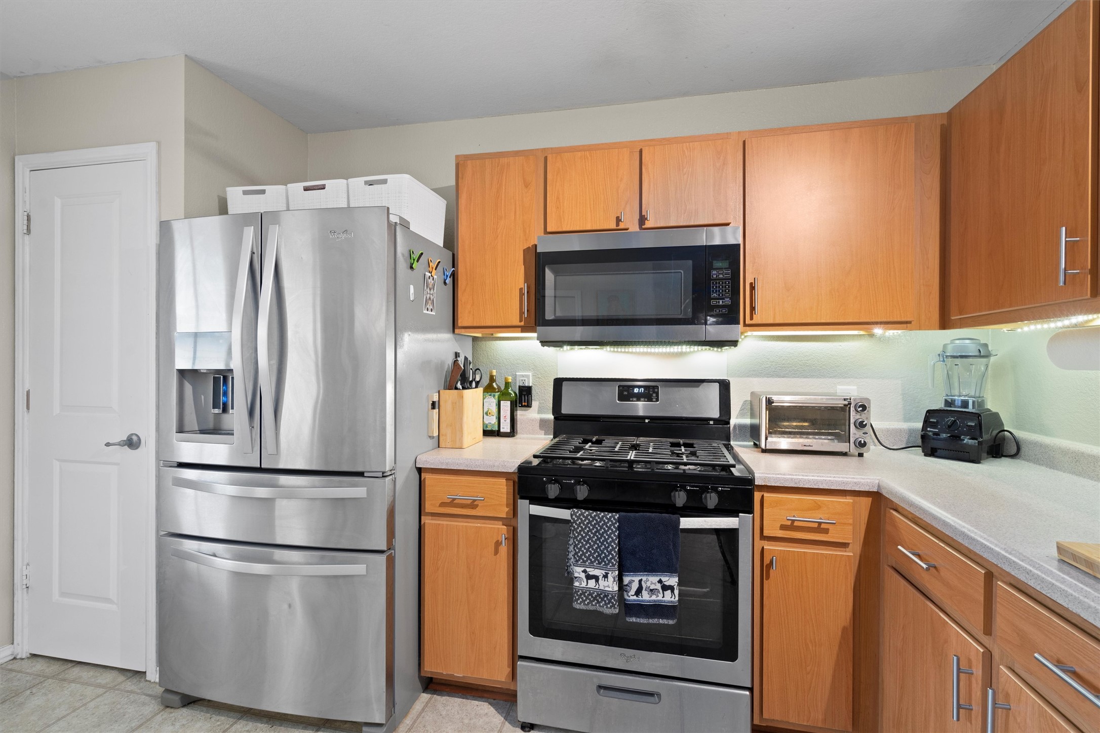 12117 Briarcreek Loop Manor, TX 78653 - Photo 10 of 29 Kitchen featuring stainless steel appliances, light countertops, and brown cabinetry