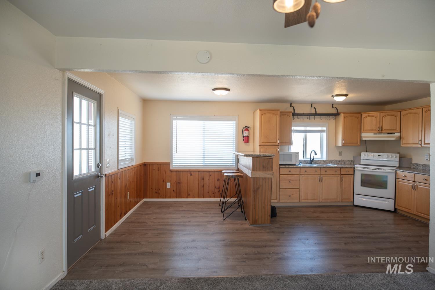 2240 Waite Road Midvale, ID 83645 - Photo 15 of 42 Kitchen with light brown cabinets, white appliances, dark wood-style floors, a wainscoted wall, and a breakfast bar area