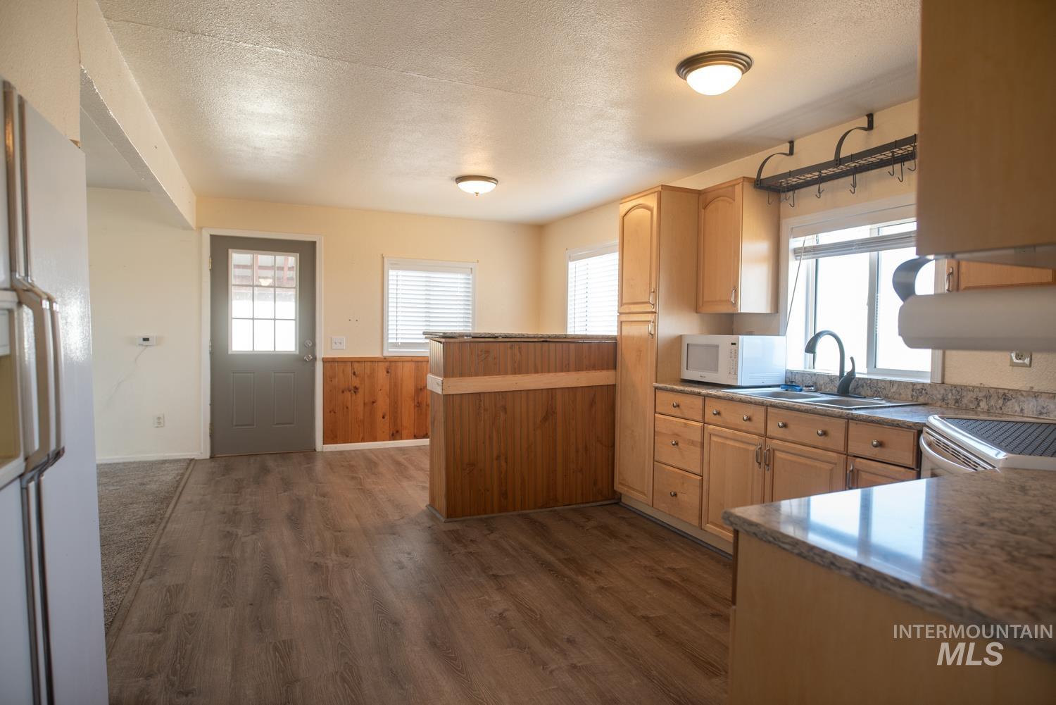 2240 Waite Road Midvale, ID 83645 - Photo 10 of 42 Kitchen with a peninsula, dark wood-style floors, white appliances, a textured ceiling, and a wainscoted wall