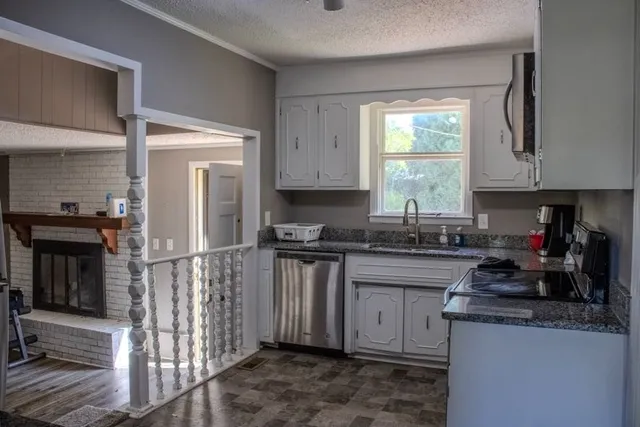 a kitchen with granite countertop a stove a sink and a microwave