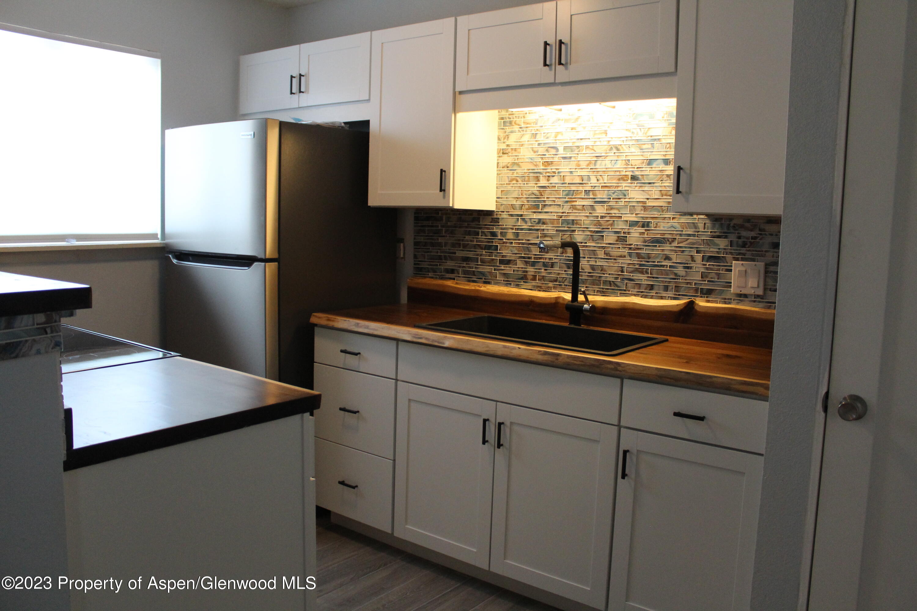 1322 East 7th Street, Unit 3 Rifle, CO 81650 - Photo 2 of 8 a kitchen with stainless steel appliances a refrigerator a sink and white cabinets