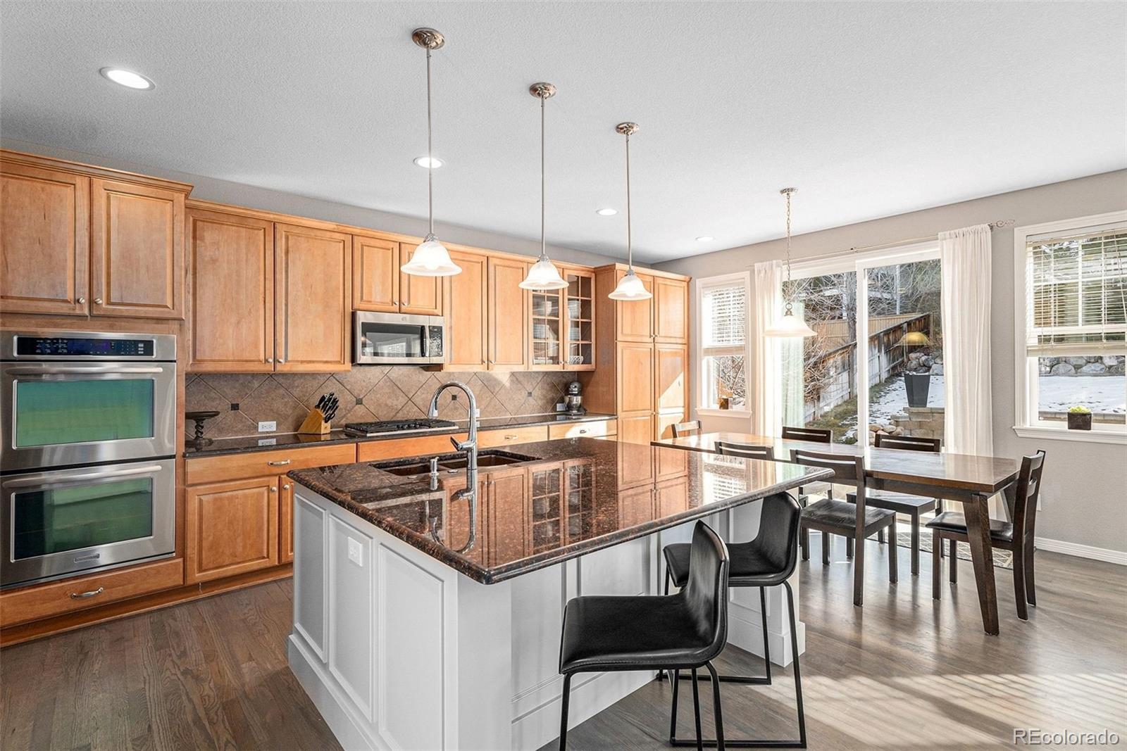 10869 Valleybrook Circle Highlands Ranch, CO 80130 - Photo 4 of 46 a kitchen with stainless steel appliances granite countertop a stove a sink a microwave a dining table and chairs