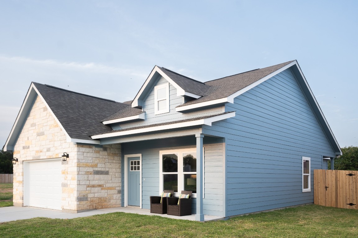 View of front of property with a shingled roof, an attached garage, and stone siding