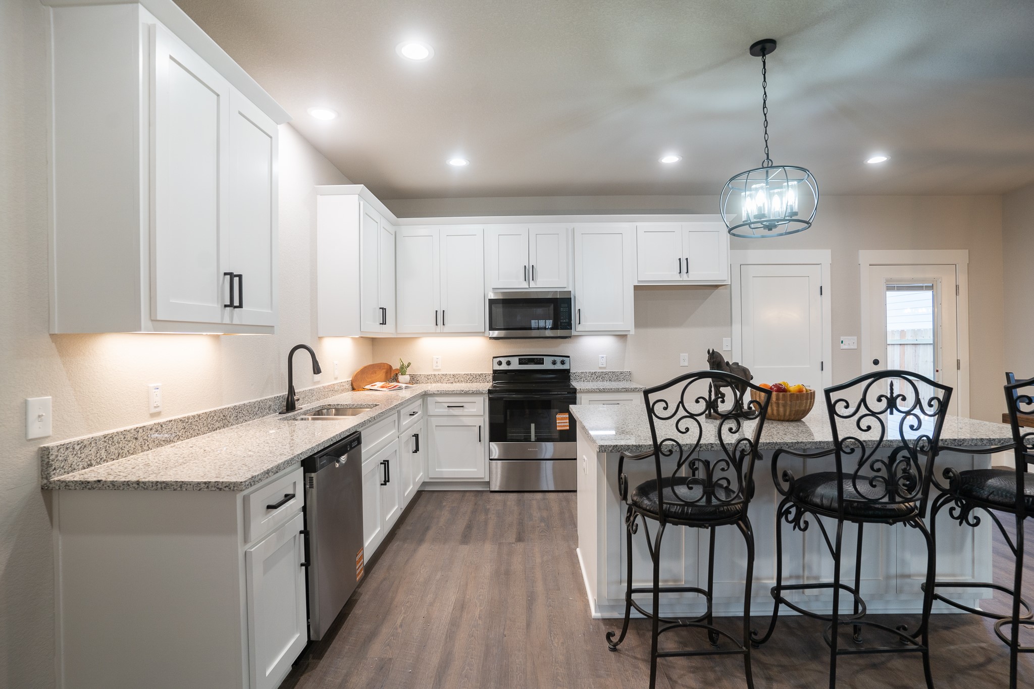 306 String Prairie Way Smithville, TX 78957 - Photo 12 of 25 Kitchen featuring appliances with stainless steel finishes, a sink, a breakfast bar area, white cabinets, and recessed lighting