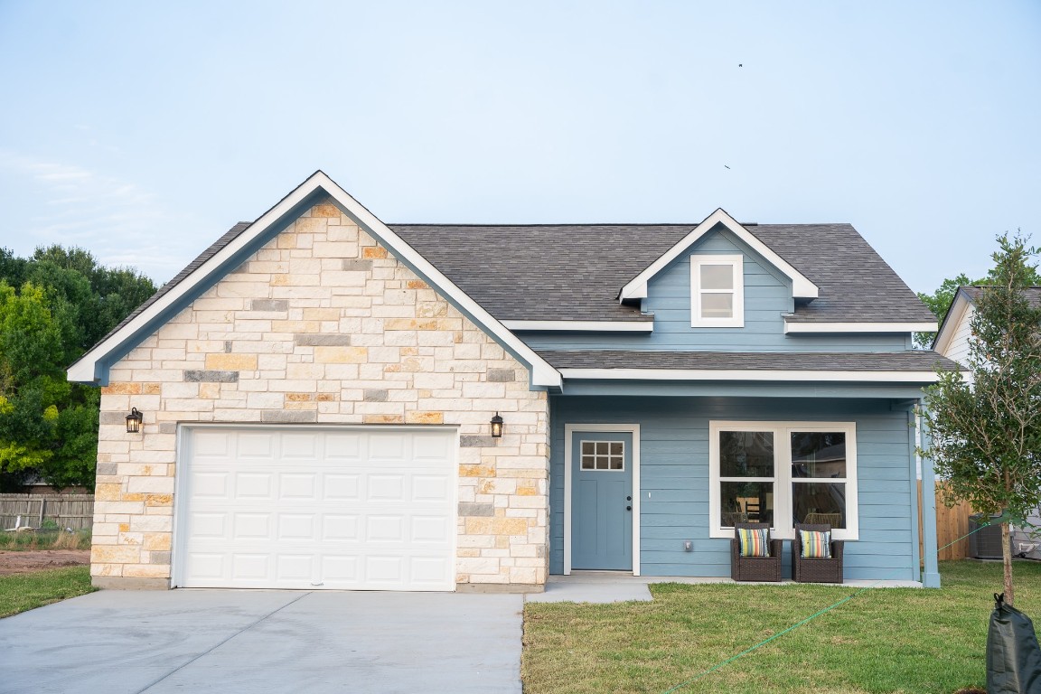 306 String Prairie Way Smithville, TX 78957 - Photo 2 of 25 View of front facade featuring concrete driveway, roof with shingles, a garage, and stone siding