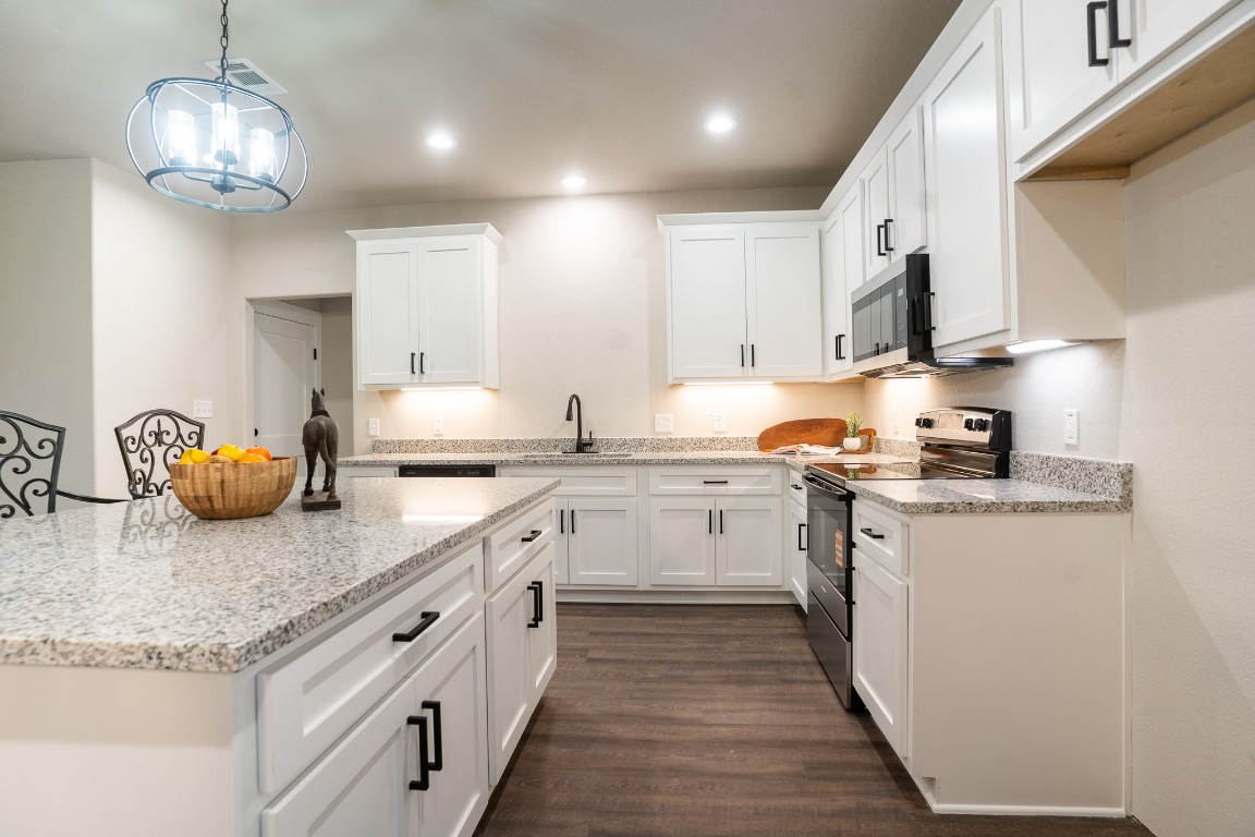 306 String Prairie Way Smithville, TX 78957 - Photo 7 of 25 Kitchen with stainless steel appliances, a sink, white cabinetry, dark wood-style floors, and hanging light fixtures