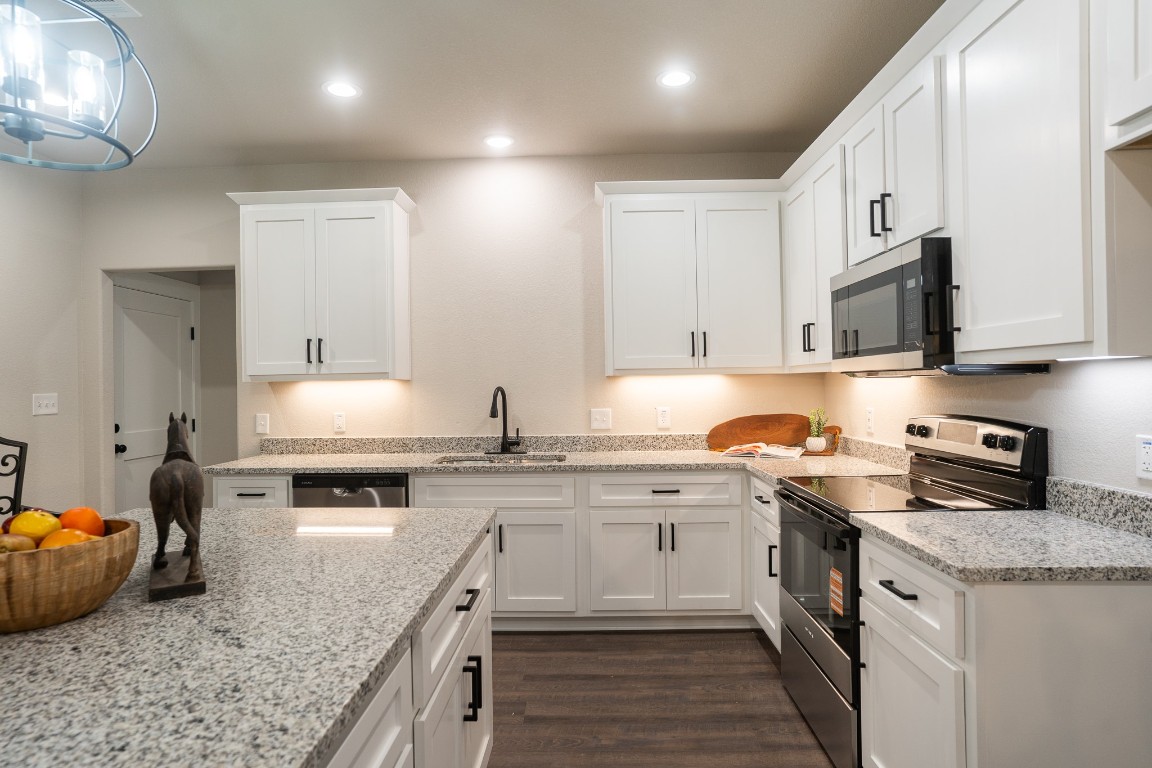 306 String Prairie Way Smithville, TX 78957 - Photo 10 of 25 Kitchen featuring stainless steel appliances, a sink, white cabinets, dark wood-style floors, and recessed lighting