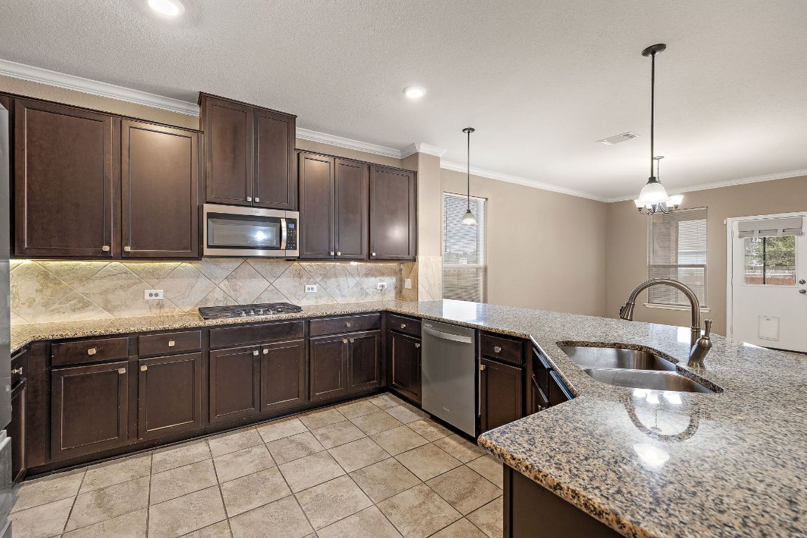1012 Plano Lane Leander, TX 78641 - Photo 4 of 21 a kitchen with kitchen island granite countertop a sink counter top space appliances and cabinets