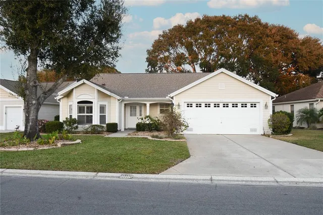a view of a white house with a yard and large trees