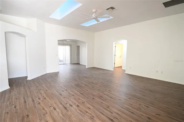 an empty room with wooden floor chandelier fan and window