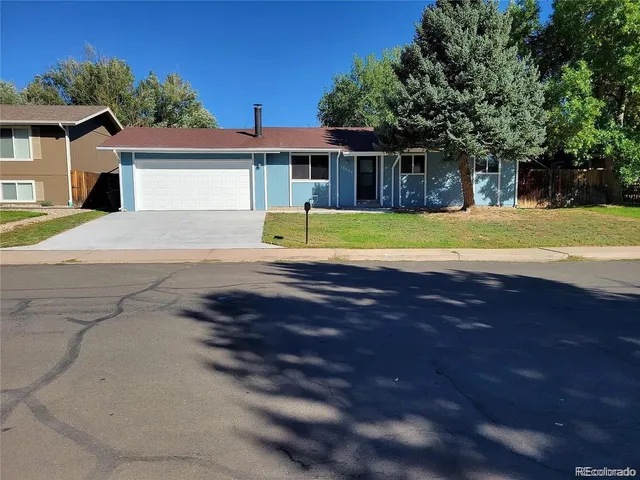 a view of a house with a yard and large tree