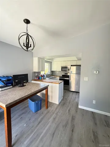 a kitchen with kitchen island granite countertop wooden floors stainless steel appliances and a counter space