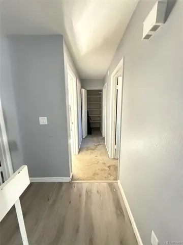 a view of a hallway with wooden floor and a livingroom