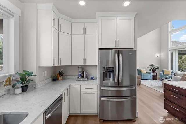 a kitchen with stainless steel appliances granite countertop a refrigerator a sink a stove and white cabinets