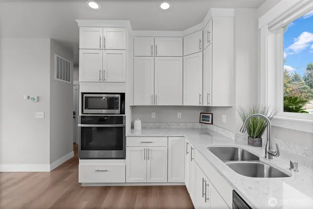 a kitchen with granite countertop white cabinets and stainless steel appliances