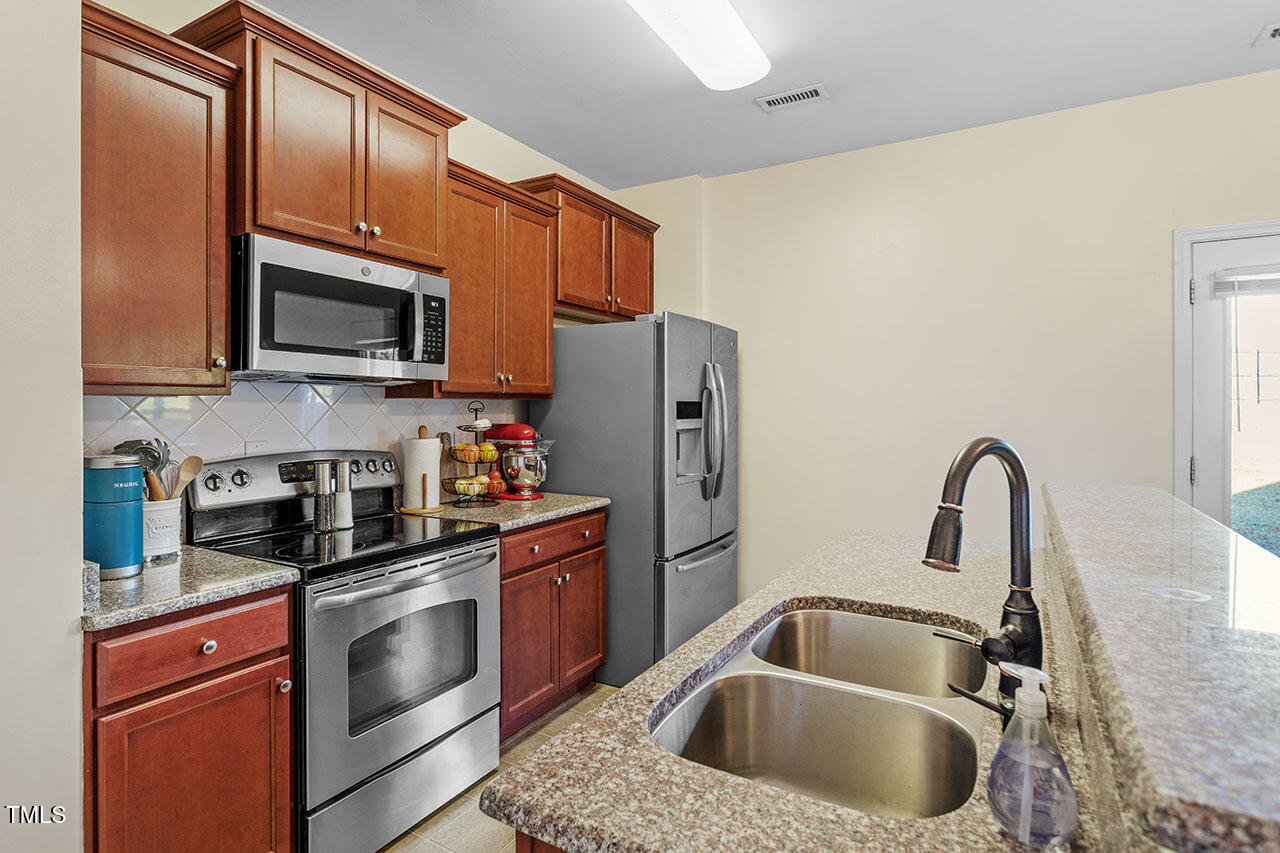 4817 Kitledge Drive Raleigh, NC 27610 - Photo 11 of 28 a kitchen with granite countertop a sink stainless steel appliances and cabinets