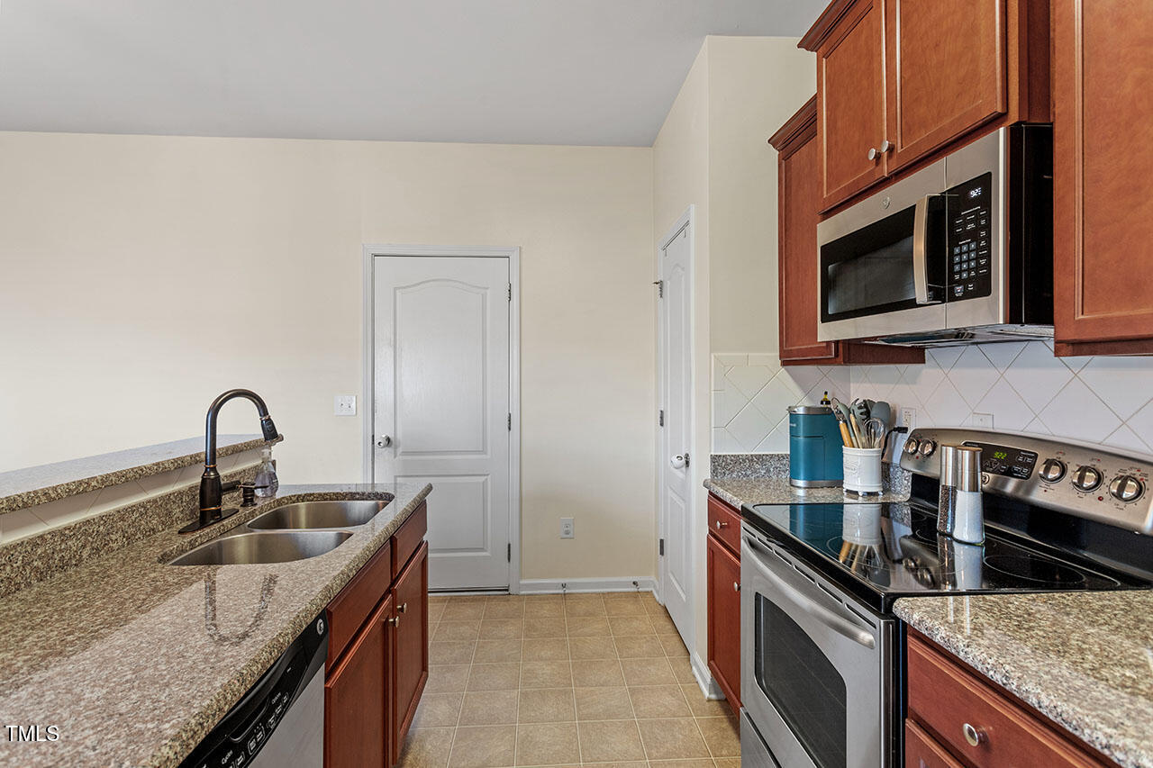 4817 Kitledge Drive Raleigh, NC 27610 - Photo 14 of 28 a kitchen with stainless steel appliances granite countertop a sink stove and microwave
