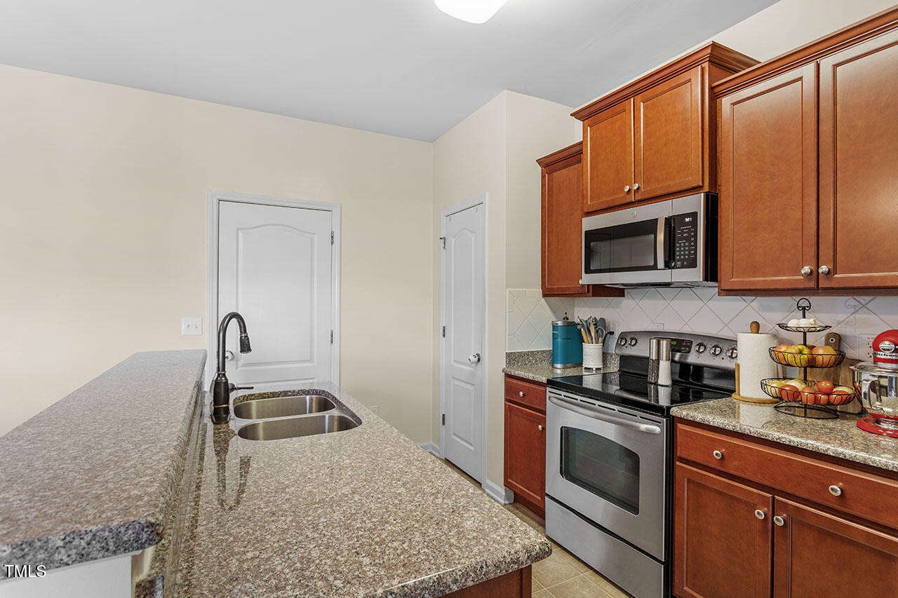 4817 Kitledge Drive Raleigh, NC 27610 - Photo 10 of 28 a kitchen with stainless steel appliances granite countertop a sink stove and microwave