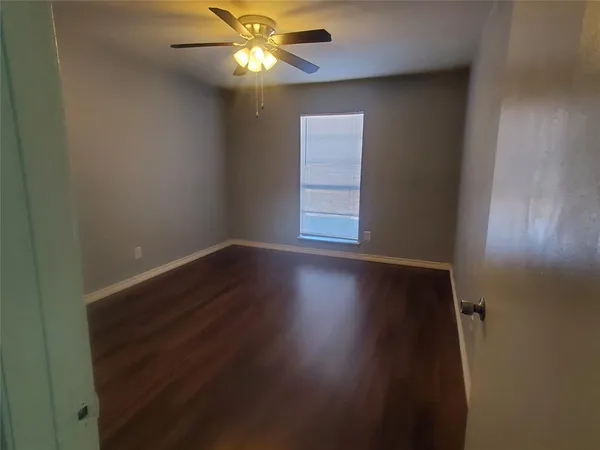 an empty room with wooden floor fan and windows