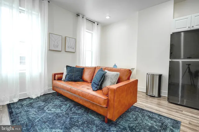 a living room with furniture and a refrigerator