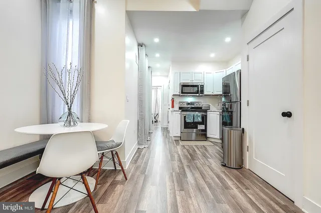 a kitchen with stainless steel appliances a dining table chairs and wooden floor