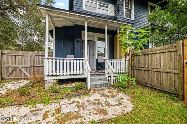 a view of a wooden house with a small yard and wooden fence