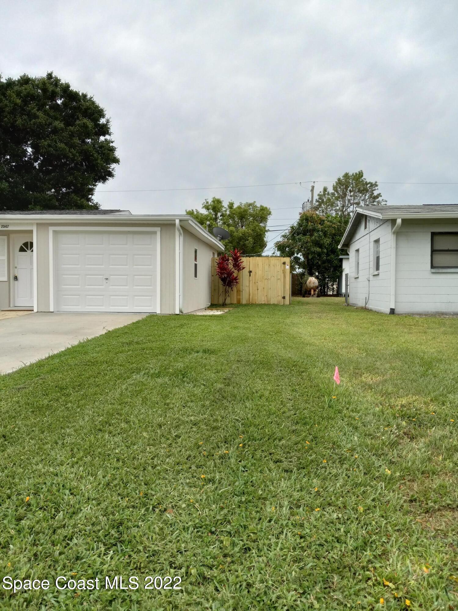 2567 Coventry Road Melbourne, FL 32935 - Photo 6 of 9 a view of a house with a yard and garage