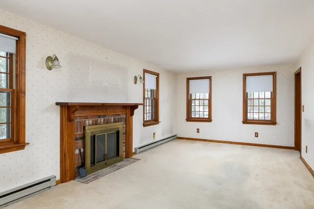 an empty room with windows and fireplace