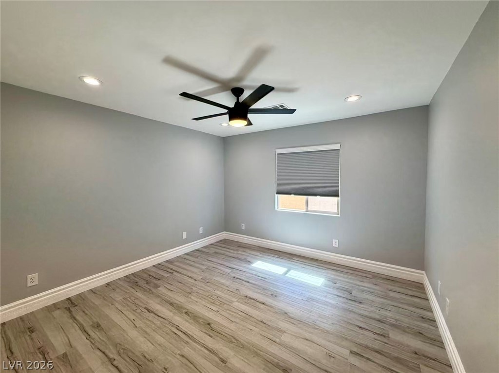 135 Tall Ruff Drive Las Vegas, NV 89148 - Photo 21 of 29 A quiet secondary bedroom features light wood-look flooring and a modern ceiling fan with recessed lighting.