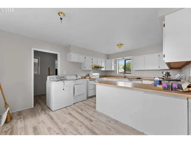 a kitchen with granite countertop a stove top oven a sink dishwasher and a refrigerator with wooden floor