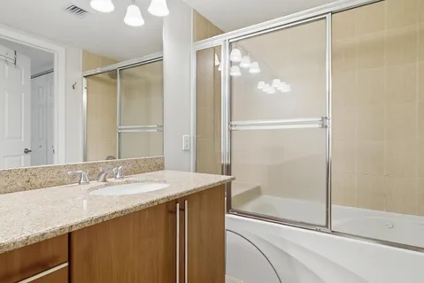 a bathroom with a granite countertop sink mirror and shower