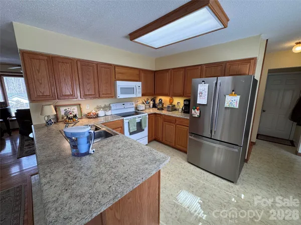 a kitchen with stainless steel appliances granite countertop a refrigerator a stove a sink a microwave and a refrigerator