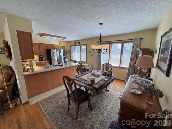 a living room with furniture a rug kitchen view and a chandelier