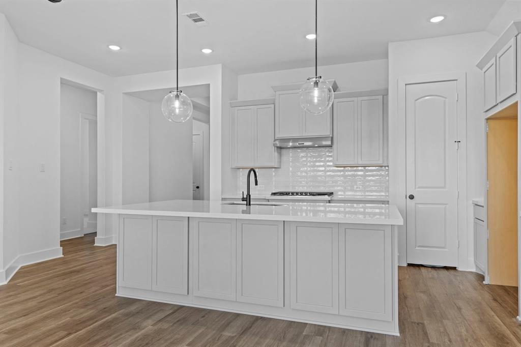 1792 Monarch Way Oak Point, TX 75068 - Photo 10 of 26 a kitchen with kitchen island white cabinets and sink